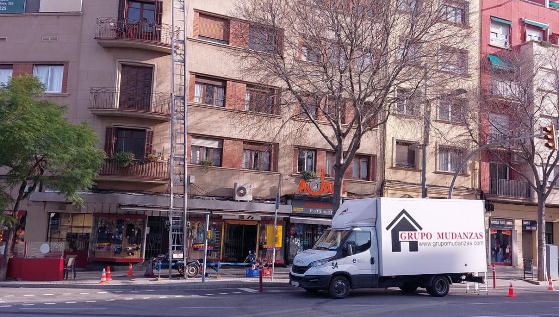 Camión de Grupo Mudanzas y elevador montamuebles realizando una mudanza en Barcelona en edificio residencial de varias plantas