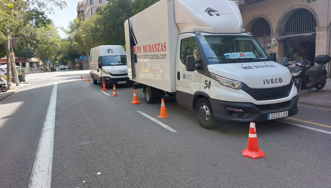 Camiones de Grupo Mudanzas realizando una mudanza en Barcelona con reserva de espacio en la vía pública y señalización de seguridad.