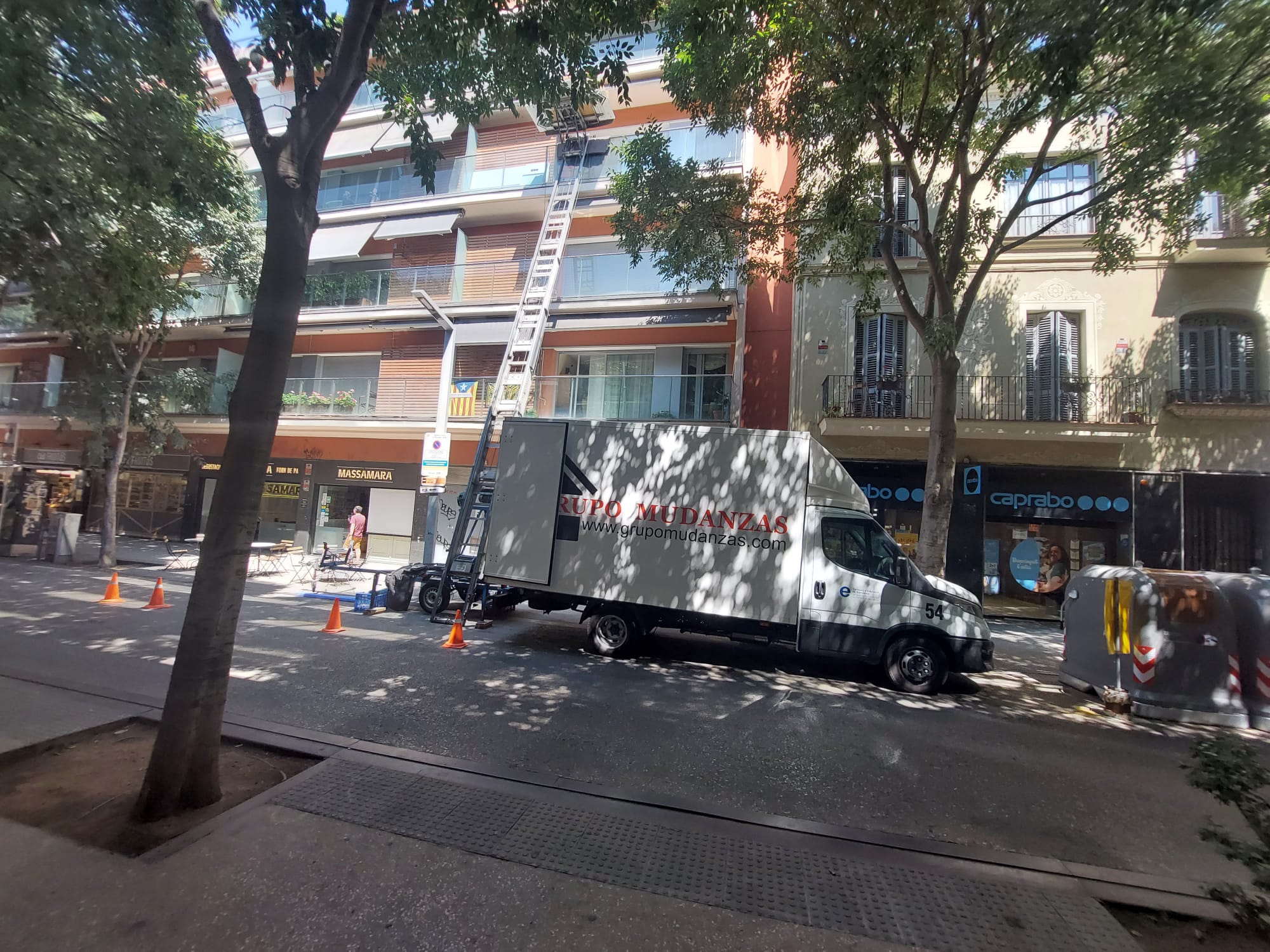 Camión de Grupo Mudanzas y elevador exterior junto a un edificio durante la operativa de mudanza