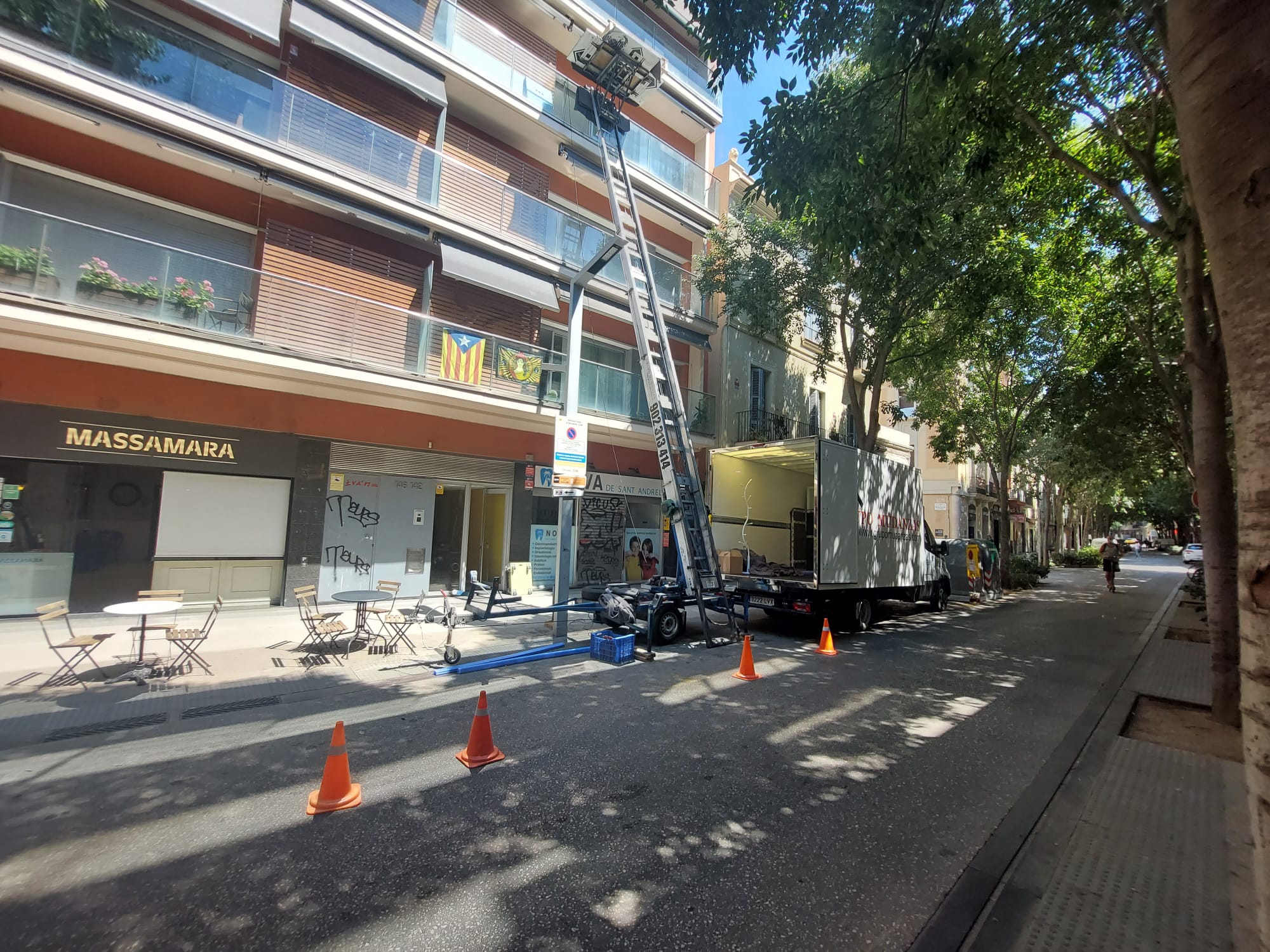 Vista lateral del camión de Grupo Mudanzas y la plataforma elevadora extendida hasta un edificio